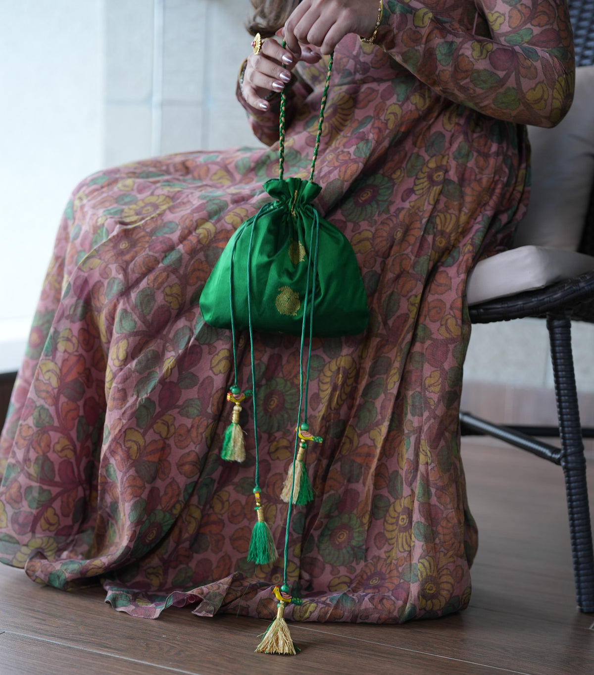 Person wearing a patterned garment with a green drawstring bag on a chair.