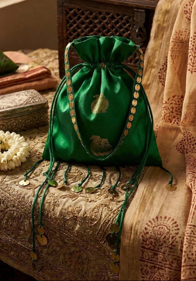Green drawstring bag with gold accents on a textured surface